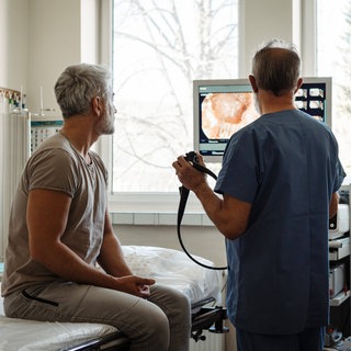 Arzt erklärt dem Patienten die Ergebnisse der Darmspiegelung