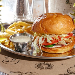 Burger mit Pommes auf einem silbernen Tablett: Eine Studie führt ein gesteigertes Risiko für 32 Erkrankungen auf den Verzehr von hochverarbeiteten Lebensmitteln zurück, darunter Diabetes Typ 2, Adipositas, Herzinfarkt oder Krebs. 