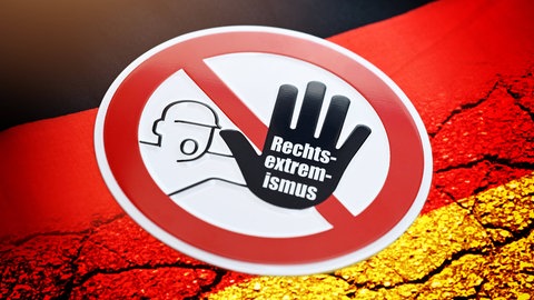 Warnschild mit der Aufschrift "Rechtsextremismus" auf einer Deutschlandfahne mit Rissen: Manche Bundesländer wollen Beamte stärker auf ihre politische Gesinnung überprüfen. In den 1970ern gab es den Radikalenerlass. Kehren Berufsverbote nun zurück?