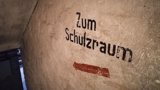 "Zum Schutzraum" steht an einer Wand im Keller eines Hauses iin Frankfurt. Durch den Angriffskrieg Russlands auf die Ukraine geraten solche Schutzräume auch in Deutschland wieder ins Bewusstsein der Bevölkerung.