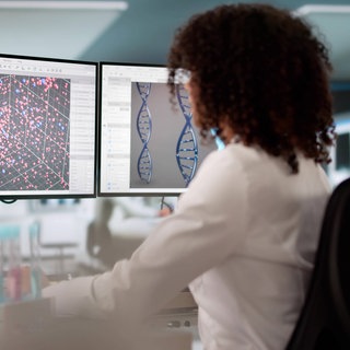 Junge Wissenschaftlerin in einem Labor vor Computerbildschirmen: Viele Wissenschaftlerinnen und Wissenschaftler in den USA spielen mit dem Gedanken auszuwandern, und deutsche Organisationen preisen den Wissenschaftsstandort Deutschland als Alternative an.