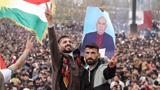 21. März 2025, Diyarbakir, Türkei: Ein Demonstrant hält bei der Newruz-Feier ein Plakat von Abdullah Öcalan, Anführer der Arbeiterpartei Kurdistans. Der hatte angekündigt,  dass die PKK den Guerillakampf gegen den türkischen Staat einstellen wird. 