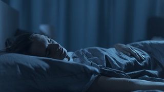 Eine Frau schläft in ihrem Bett