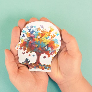 Hände halten behutsam Kopfsilhouette, darin bunte Puzzleteile als Gehirn: Autismus, ADHS, Tourette: Manche Menschen denken, fühlen, handeln anders als die Mehrheit. Aber Neurodiversität ist Teil menschlicher Vielfalt.