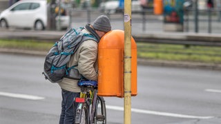 Ein Mann steckt auf der Suche nach Pfandflaschen sein Gesicht in einen öffentlichen Mülleimer: Armut macht nicht nur krank, sondern verkürzt auch die Lebenserwartung. Bei Frauen in Deutschland um rund vier Jahre, bei Männern um etwa sieben. 