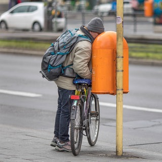 Ein Mann steckt auf der Suche nach Pfandflaschen sein Gesicht in einen öffentlichen Mülleimer: Armut macht nicht nur krank, sondern verkürzt auch die Lebenserwartung. Bei Frauen in Deutschland um rund vier Jahre, bei Männern um etwa sieben. 