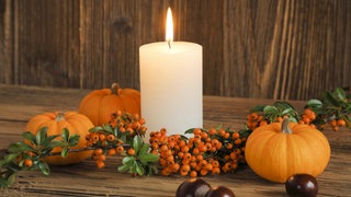 Herbstdekoration mit brennender Kerze, Kürbissen, Feuerdorn und Kastanien: Warum wird Wachs transparent, wenn es flüssig wird?