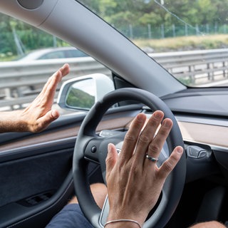 Mann fährt mit dem Tesla Model Y Auto auf der Autobahn mit Autopilot ohne Hände am Lenkrad: Automatisiertes und autonomes Fahren kann helfen, Menschen und Güter in Zukunft nachhaltiger zu transportieren. 