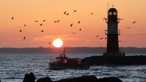 Symbolbild: Kurz vor Sonnenaufgang fährt ein Fischer auf die Ostsee hinaus