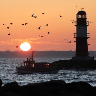 Symbolbild: Kurz vor Sonnenaufgang fährt ein Fischer auf die Ostsee hinaus
