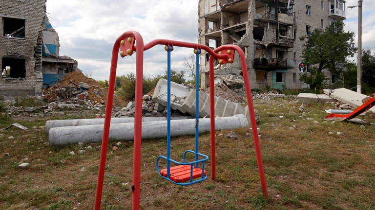 Leere Schaukel in einem durch den Beschuss russischer Truppen zerstörten Wohnblock bei Charkiw: Seit Beginn des russischen Angriffskrieges gegen die Ukraine 2022 wurden tausende ukrainische Kinder nach Russland verschleppt. (Symbolbild) 