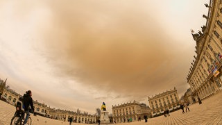 Saharastaub färbt den Himmel über einer Stadt gelb. In der Wissenschaft forscht man nun mit solchen Saharastaub-Ereignissen.