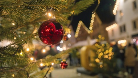 Weihnachtsmarkt in Nagold im Schwarzwald: Eine Weihnachtskugel und Lichterketten sorgen an einem Baum für Adventsstimmung.