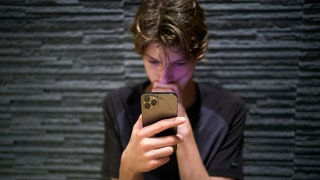 Teenager schaut gebannt auf den Bildschirm seines Smartphones: Rund 25 Prozent der 10- bis 17-Jährigen verbringen viel zu viel Zeit mit sozialen Medien. Das beeinträchtigt ihr Denken, Fühlen und Verstehen.
