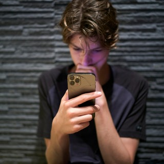 Teenager schaut gebannt auf den Bildschirm seines Smartphones: Rund 25 Prozent der 10- bis 17-Jährigen verbringen viel zu viel Zeit mit sozialen Medien. Das beeinträchtigt ihr Denken, Fühlen und Verstehen.
