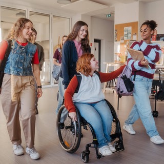 Schülerinnen, eine davon im Rollstuhl, auf dem Flur einer Schule: Eltern haben die Wahl, wo ihr Kind mit Förderbedarf zur Schule gehen soll. Doch Inklusion an Schulen hapert immer noch an baulichen Einschränkungen, fehlendem Personal, am Geld.