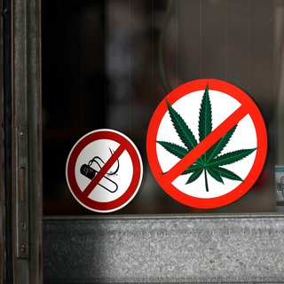 Aufkleber an der Eingangstür eines Restaurants zeigen: Rauchen und Konsum von Cannabis verboten. Ein Blick in die Geschichte der Drogenprohibition zeigt: Die Entscheidung, ob eine berauschende Substanz legal oder illegal ist, ist oft willkürlich.