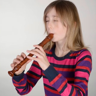 Mädchen spielt mit geschlossenen Augen Blockflöte