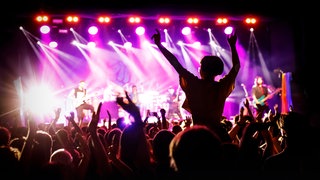 Publikum tanzt bei einem Open-Air-Konzert vor der Bühne: Trotz Streaming-Boom erlebt Live Musik eine Renaissance, weil sie Körper, Gehirn und Gemeinschaft stärker aktiviert als jede Aufnahme.