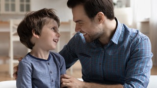 Vater mit kleinem Sohn im vertraulichen Gespräch: Sexualaufklärung ist wichtig. Altersgerechte Begriffe wie Penis oder Vulva helfen, Scham zu vermeiden und stärken den Schutz vor Missbrauch, weil Kinder Dinge klar benennen können.