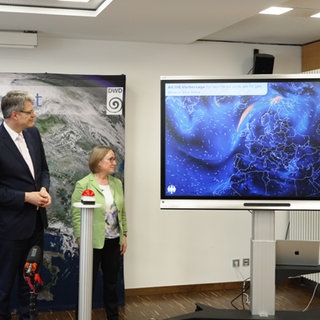 Roland Potthast (l-r), Leiter des Referats für die Entwicklung von «Aicon», Patrick Schnieder (CDU), Bundesverkehrsminister, und Sarah Jones, Präsidentin des Deutschen Wetterdienstes (DWD), schauen auf einen Bildschirm, der die Leistungsfähigkeit von «Aicon» darstellt. Der Bundesverkehrsminister hat den offiziellen Startschuss für das KI gestützte, globale Vorhersagemodell «Aicon» des Deutschen Wetterdienstes (DWD) gegeben.