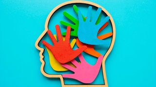 Umriss eines Kopfes mit farbigen Handflächen im Inneren. Abstraktes Symbol für Autismus oder Neurodiversität: Über autistische Menschen gibt es viele Vorurteile und oft wenig Wissen