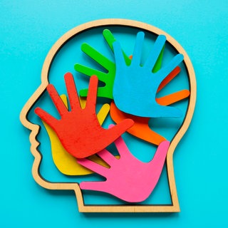 Umriss eines Kopfes mit farbigen Handflächen im Inneren. Abstraktes Symbol für Autismus oder Neurodiversität: Über autistische Menschen gibt es viele Vorurteile und oft wenig Wissen