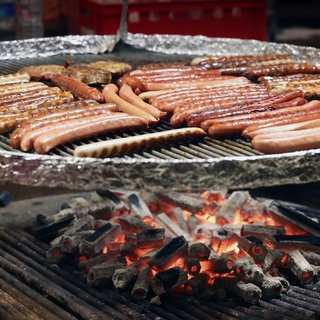 Symbolbild: Holzkohlegrill mit Würstchen auf einem Weihnachtsmarkt