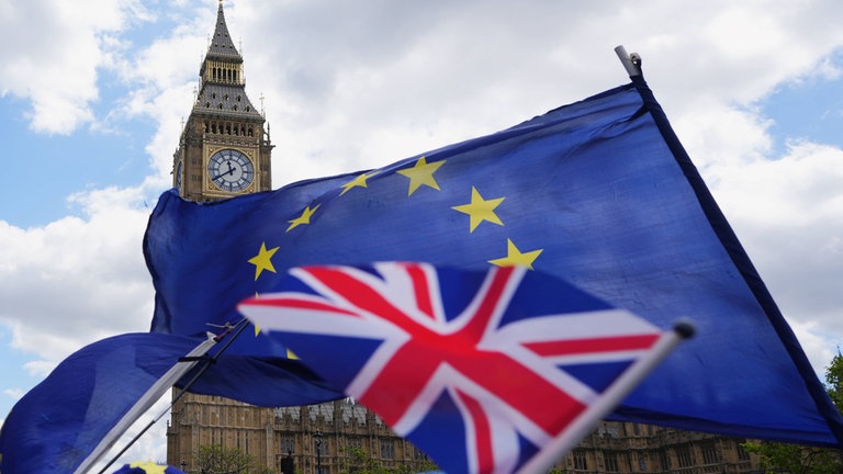 Pro-EU-Aktivisten schwenken im Mai 2026 Fahnen in der Nähe des Parlaments in London: Vor zehn Jahren stimmten die Briten für den Brexit; mit weitreichenden Folgen. Nun sieht es nach einer Annährung aus.
