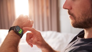 Symbolbild: Mann mit Schlaftracker im Bett