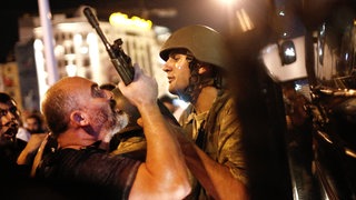 Ein Mann packt den Gewehrlauf eines Soldaten: Türkische Polizisten nehmen am 16. Juli 2016 auf dem Taksim-Platz in Istanbul türkische Soldaten fest. 