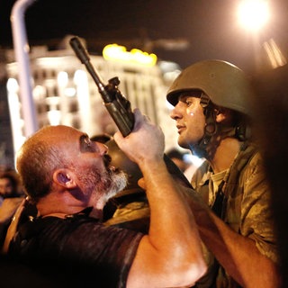 Ein Mann packt den Gewehrlauf eines Soldaten: Türkische Polizisten nehmen am 16. Juli 2016 auf dem Taksim-Platz in Istanbul türkische Soldaten fest. 