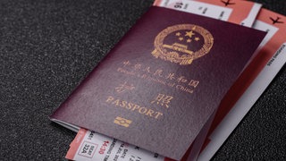 Symbolbild: Chinesischer Reisepass mit Tickets als Hintergrund 