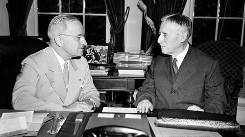 US-Präsident Harry Truman (linkts) nach seiner Rückkehr von der Potsdamer Konferenz an seinem Schreibtisch im Weißen Haus mit Kriegsminister Henry L. Stimson. Die Männer diskutieren über die Atombombe, die auf die japanische Stadt Hiroshima abgeworfen wurde.
