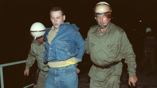 Zwei Polizisten führen einen Mann ab: Zu schweren Ãbergriffen von Rechtsradikalen auf Ausländerheime in Hoyerswerda und weiteren Orten Sachsens und anderen ostdeutschen Bundesländern kam es in den Tagen um den 22.9.1991. In Hoyerswerda, wo Rechtsextremisten die Polizei angriffen und sich mit Gegendemonstranten prügelten, wurden zahlreiche Personen festgenommen. 