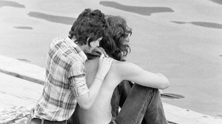 Junges Paar sitz an einem Ufer, Anfang 1970er-Jahre