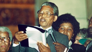 Der Führer der südafrikanischen Befreiungsbewegung ANC, Nelson Mandela (Mitte), hält nach seiner Freilassung aus dem Gefängnis am 11.2.1990 eine Rede in Kapstadt. Hinter ihm seine Frau Winnie Mandela. Der spätere Nobelpreisträger und Politiker wurde der erste schwarze Staatspräsident des Landes (1994-1999). Er wurde 1964 wegen seines Kampfes gegen das Apartheidregime zu lebenslanger Haft verurteilt und 1990 freigelassen. 1993 bekam er gemeinsam mit Präsident Frederik de Klerk den Friedensnobelpreis.