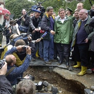 Im Sommer 2002 traten die Elbe und ihre Zuflüsse über die Ufer. Das Jahrhunderthochwasser hinterließ eine Schneise der Verwüstung. Tausende Menschen verloren ihr Hab und Gut. Bundeskanzler Gerhard Schröder besuchte am 14. August die Stadt Grimma in Sachsen in Regenjacke und Gummistiefeln.