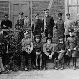 August Euler (1868 - 1957, hier mit Brille) mit Schülern der von ihm gegründeten Fliegerschule in Griesheim bei Darmstadt, neben ihm (mit Hund) Prinz Heinrich von Preußen. Foto um 1910