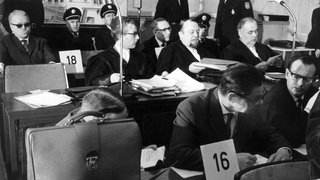 Blick auf die Angeklagten und ihre Anwälte im Frankfurter Auschwitz-Prozess: Hinten links der Angeklagte Viktor Capesius, hinten rechts Wilhelm Boger (Archivfoto vom 3. April 1964). Mit dem KZ Auschwitz, weltweites Symbol für die NS-Gräuel, befasste sich ein Frankfurter Schwurgericht zwischen 1963 und 1965. Dieser "große" Auschwitz-Prozess – ihm folgten noch weitere kleinere – endete mit lebenslangem Zuchthaus für 6 der 20 Angeklagten.