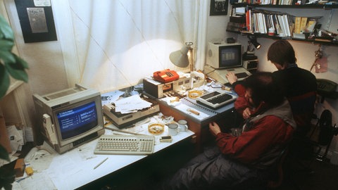 Wau Holland (links) und Steffen Wernery vom "Chaos Computer Club" in Hamburg an ihren Computern im November 1984. Um zu demonstrieren, dass das BTX-System der Post nicht ohne Fehlerquellen ist, haben Mitglieder des Clubs mit Infos über die Hamburger Sparkasse, die zufällig im System "herumirrten", die Bank mit 135.000 D-Mark zu ihren Gunsten belastet.