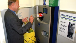 Bundesumweltminister Juergen Trittin steckt 2003 eine Flasche in einen Getränkeautomaten