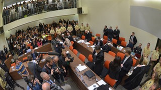 Die Angeklagte Beate Zschäpe (Gruppe rechts unten in der Mitte) steht vor Beginn des Prozesses am 6. Mai 2013 im Gerichtssaal in München neben ihren Anwälten Wolfgang Stahl (links), Wolfgang Heer und Anja Sturm (rechts) und dreht den Zuschauern den Rücken zu.