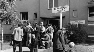 Schlange im Notaufnahmelager Marienfelde am 1. September 1958 in West-Berlin. Das Aufnahmelager für Flüchtlinge aus der DDR und Ost-Berlin war 1952  1953 erbaut worden. Ende August 1958 erreichten die Flüchtlingszahlen mit 3.000 Menschen innerhalb von drei Tagen eine neue Rekordhöhe: Blick auf die Reihe von Menschen, die im Notaufnahmelager Marienfelde auf ihre Registrierung warten.