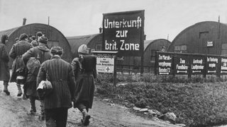 Heimkehrer gehen im Lager Friedland auf die als Notunterkünfte dienenden Nissenhütten zu (Archivfoto von 1946). Am 26. September 1945 eröffnete die britische Armee in dem Ort Friedland bei Göttingen ein Auffanglager.