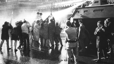 Ein Pulk Demonstranten mit Kreuz vor einem Wasserwerfer am 14.04.1968, Ostersonntag, auf dem Kurfürstendamm in Berlin. Eine Welle von Protestdemonstrationen hat das Attentat auf den Berliner SDS-Ideologen Rudi Dutschke ausgelöst.
