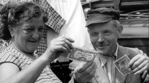 Das Archivbild vom 06.07.1959 zeigt ein Ehepaar auf dem Saarbrücker Markt, das neue und alte Geldscheine vergleicht. In 519 Umtauschstellen konnten die Bewohner des Saarlandes ihre französischen Francs in D-Mark tauschen. Das Saarland entwickelte sich seit dem Anschluß an die Bundesrepublik - nicht zuletzt dank Bonner Milliardenspritzen - vom einstigen Armenhaus der Nation zu einer fortschrittlichen Europa-Region.