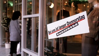 Auslagen in einem Schaufenster einer Boutique in Mainz, November 1996. "Bei uns ist langer Donnerstag. Wir sind bis 20.30 Uhr für Sie da!"