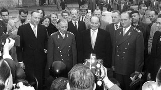Adolf Heusinger, Bundesverteidigungsminister Theodor Blank und Alfred Speidel (v. l. n. r.) während der Feierstunde am 12. November 1955 in der Ermekeil-Kaserne Bonn im Mittelpunkt des Interesses der Fotografen. Die ersten Soldaten der neuen deutschen Streitkräfte erhielten an diesem Tag von Minister Blank ihre Ernennungsurkunden. 