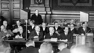 Die führenden Männer des Reichsrundfunks wurden, soweit sie als NS-Gegner bekannt waren, nach der Machtergreifung verhaftet und am 5. November 1933 vor Gericht gestellt. Staatssekretär Dr. Hans Bredow (stehend) während seiner Aussage, rechts von ihm sitzend Dr. Kurt Magnus, Direktor der Reichsrundfunkgesellschaft. 2. Reihe die Verteidiger und in der vorderen Reihe die weiteren Angeschuldigten von links: Zorek, Korte, Dr. Jaeger, Dr. Kohl, Dr. Otto und Intendant Flesch.